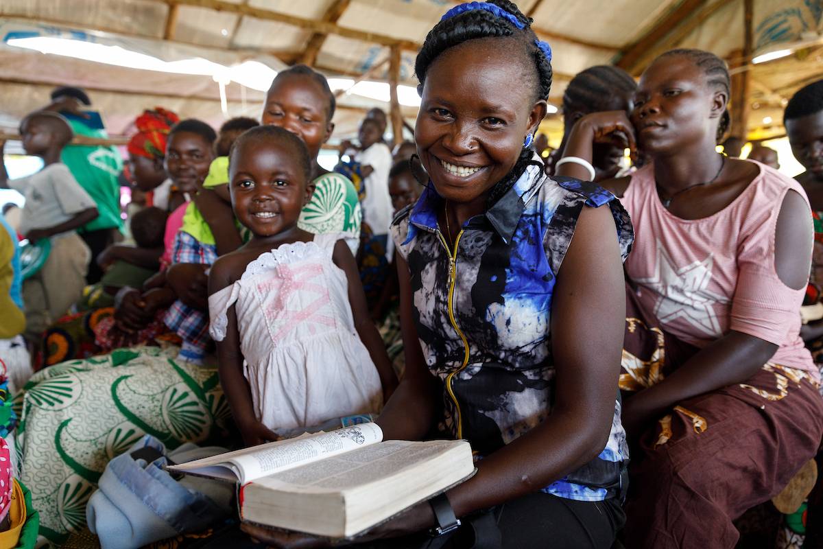 Ugandan woman smiling with her Bible in church.